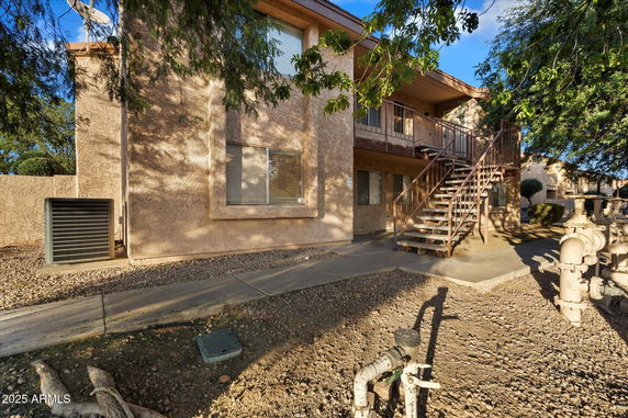 Front view of a two-story building with an external staircase and beige stucco exterior.