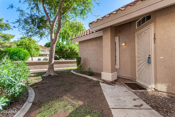 Front view of a single-story house with a brown exterior and a metal front door.