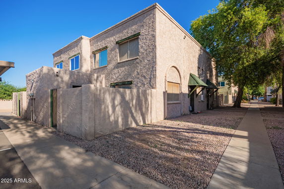 Front view of a two-story stucco house with green awnings.