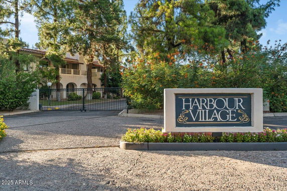 Front view of a gated residential community entrance with a sign reading 'Harbour Village'.