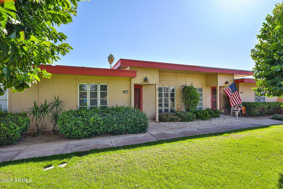 Front view of a single-story house with a flat roof and red trim.