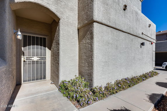Front view of a building entrance with a security screen door and adjacent wall.