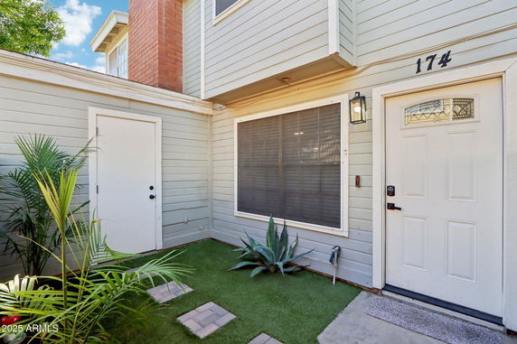 Front view of a house entryway with a light-colored door and adjacent windows.