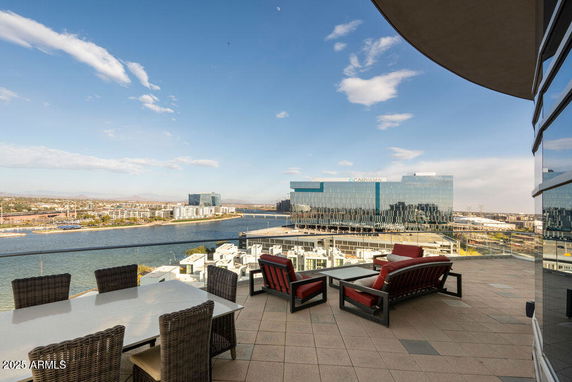 Balcony view of cityscape and waterway with outdoor furniture.