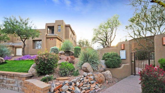 Front view of a modern multi-story house with a desert landscape garden.