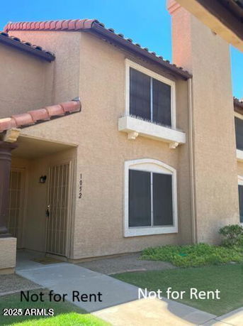 Front view of a two-story house with beige exterior and arched windows.