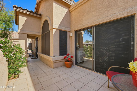 Front view of a house with large windows and tiled patio area.
