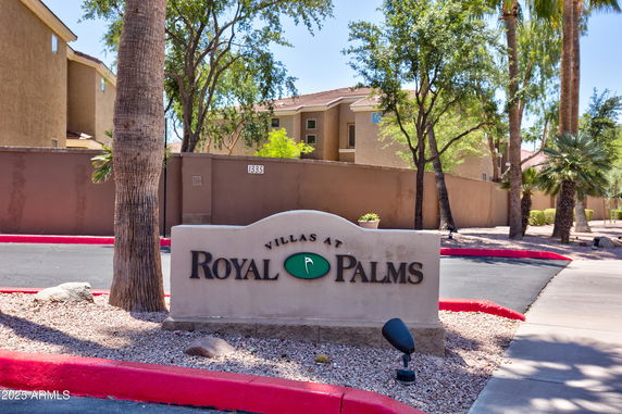 Entrance view of a residential complex with a sign reading 'Villas at Royal Palms'.