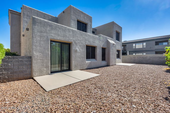 Front view of a modern two-story house with a textured exterior and sliding glass doors.