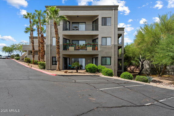 Front view of a multi-story building with balconies and palm trees.