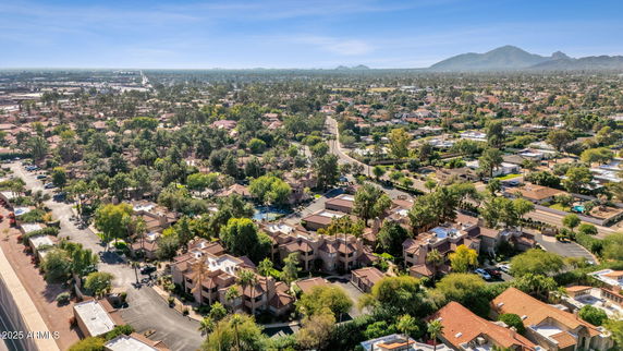 Wide-angle view of a residential area with multiple houses and greenery, set against a distant mountain backdrop.