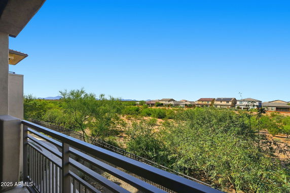 Panoramic view from a building showing surrounding greenery and houses in the distance.