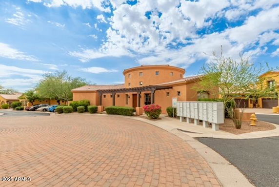 Front view of a circular, single-story building with stone pavement and a porch.