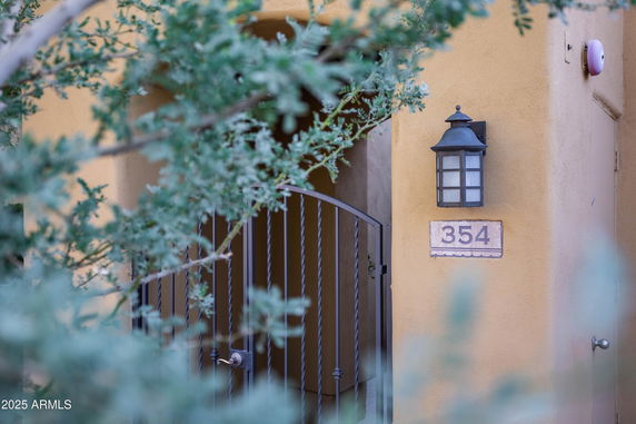 Front view of a house entrance with a gate and wall-mounted lantern.