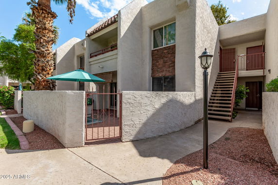 Front view of a multi-story residential building with a staircase leading to upper floors and an entrance gate.