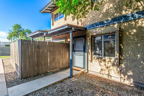 Front view of a two-story house with a wooden fence and patio.