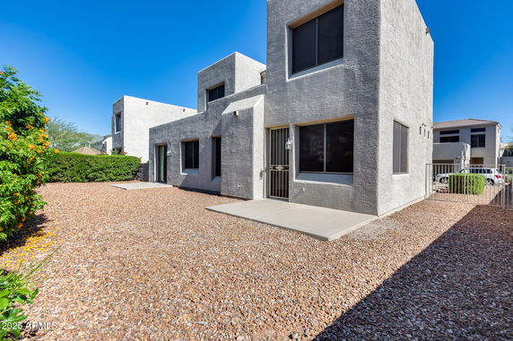 Front view of a modern two-story house with a gravel yard and large windows.