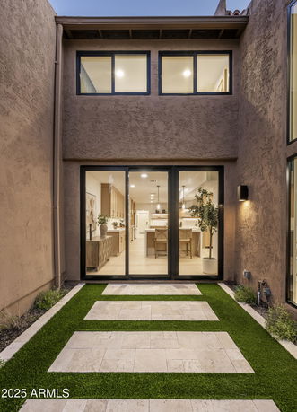 Front view of a house with large glass doors leading to an interior space.