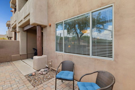 Front view of a house with large windows and patio seating.