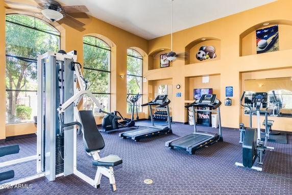 Interior of a fitness room with gym equipment, treadmills, and large windows.