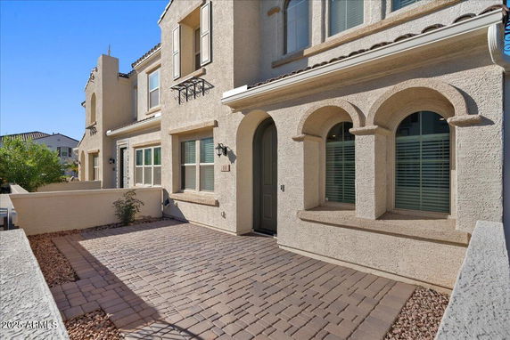 Front view of a two-story house with arched windows and a paved pathway.