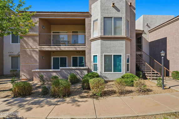 Front view of a two-story apartment building with balconies and a staircase.