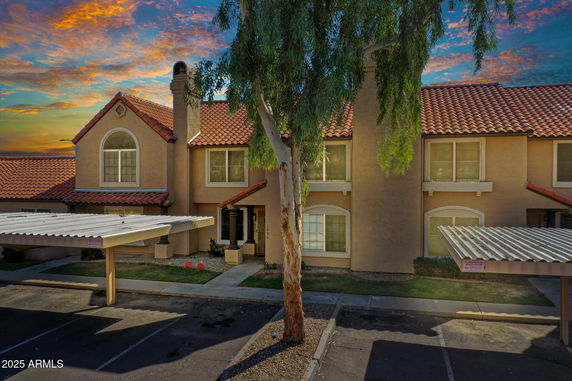 Front view of a two-story house with a red tile roof and covered parking area.
