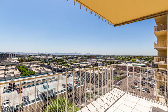 Balcony view overlooking a cityscape with buildings and distant mountains.