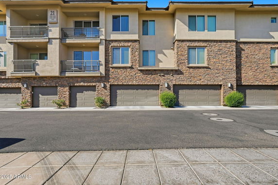 Front view of a multi-story residential building with balconies and garages.