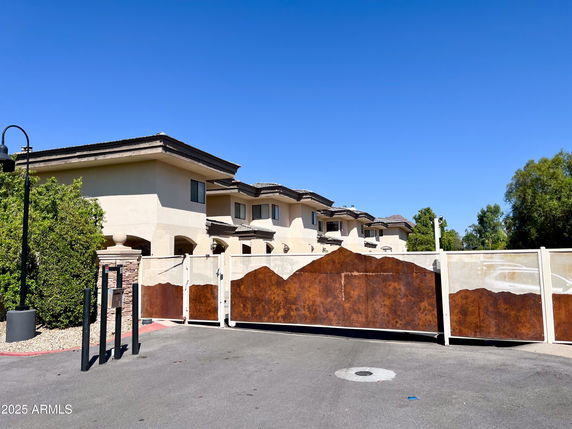 Front view of a multi-story building with an artistic gate and beige facade.