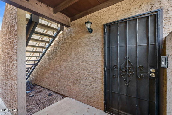 Exterior view of a staircase and front metal door in a building entrance.