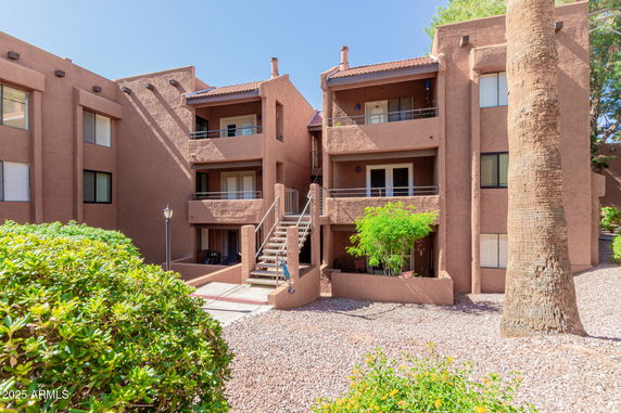Front view of a multi-story apartment complex with balconies and external staircases.