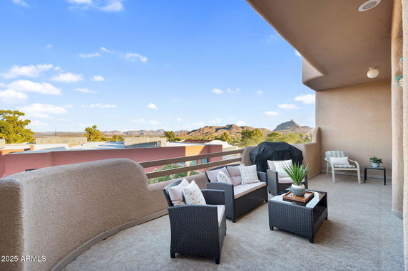 Outdoor balcony with seating and mountain view.