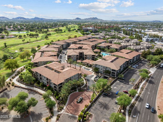 Panoramic view of an apartment complex surrounded by greenery and distant mountains.