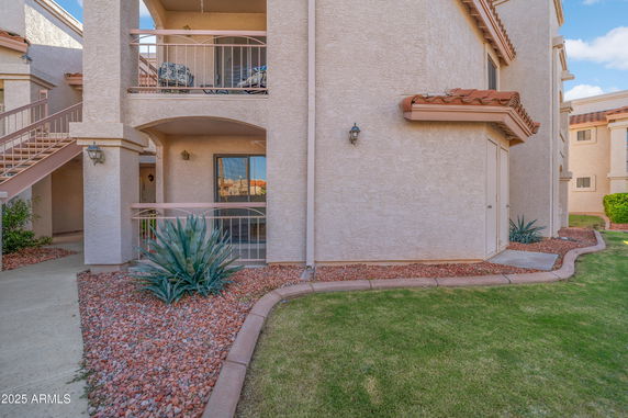 Front view of a beige multi-story building with balconies and outdoor stairs.