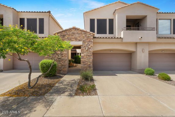 Front view of a modern two-story house with stone and stucco exterior and two garages.