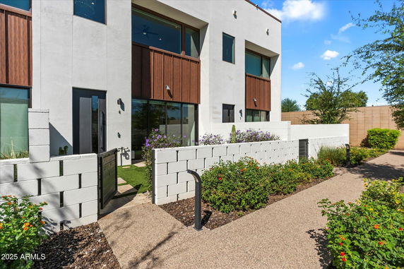 Front view of a multi-story building with modern design and a small garden.