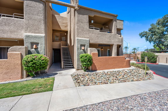 Front view of a multi-story apartment building with exterior staircases and balconies.