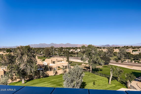 Wide-angle view of a residential area with greenery and mountains in the background.