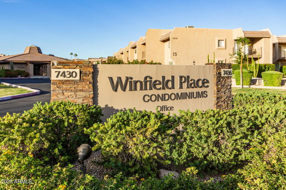Front view of a condominium complex sign and building.
