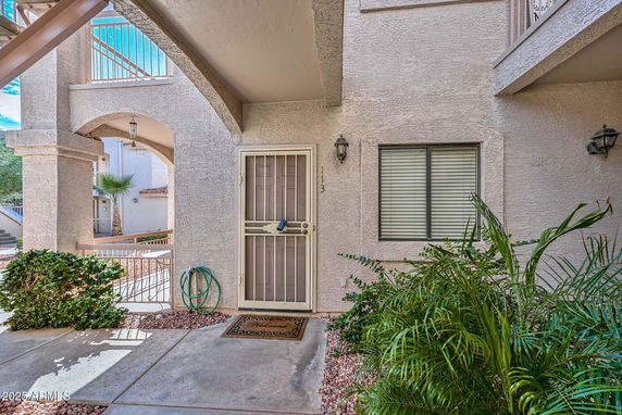 Front view of an entrance to an apartment with a metal security door and window with blinds.