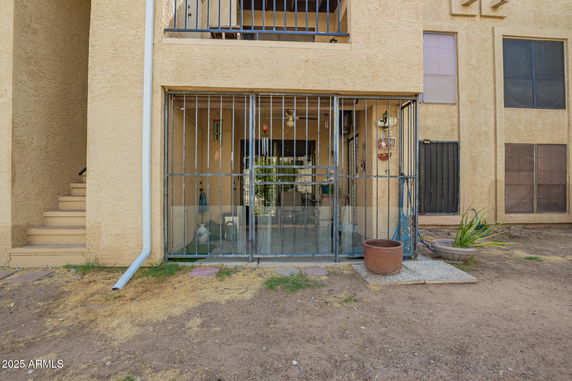 Front view of a building with a gated patio and stairs leading to the upper level.