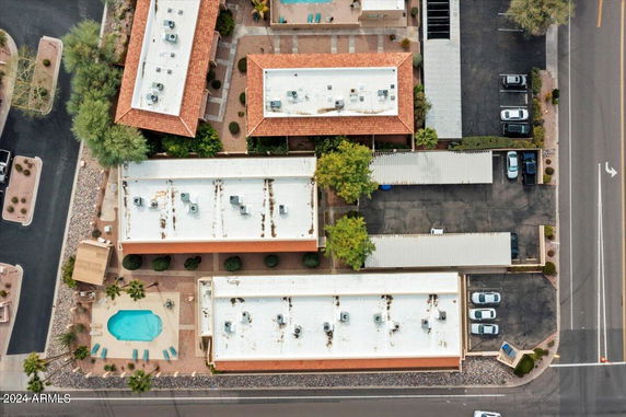 Aerial view of a residential complex with multiple buildings, a swimming pool, and parking area.
