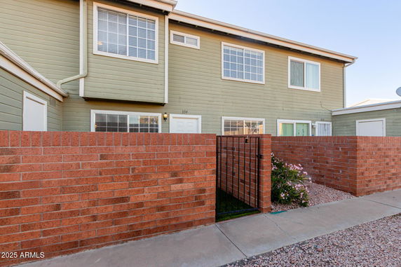 Front view of a two-story townhouse with a brick fence.
