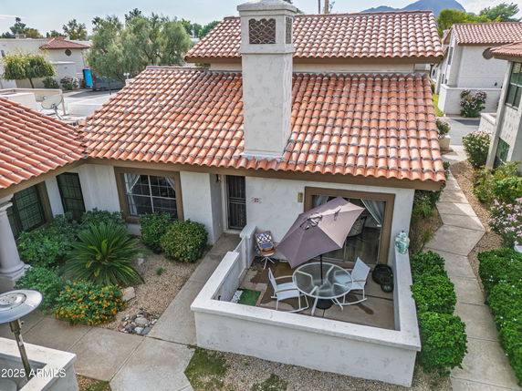 Front view of a single-story house with a tiled roof and a small patio area.