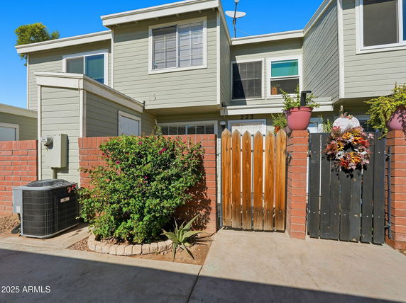 Front view of a two-story house with a wooden gate and brick walls.