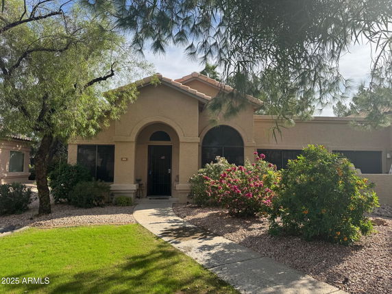 Front view of a single-story house with arched entry and landscaped garden.