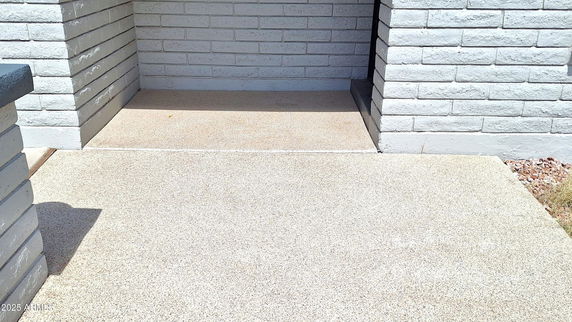 Front entrance of a house with brick walls and a concrete pathway.