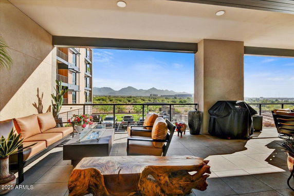 Outdoor patio area with lounge furniture and a grill overlooking a scenic landscape and mountains.