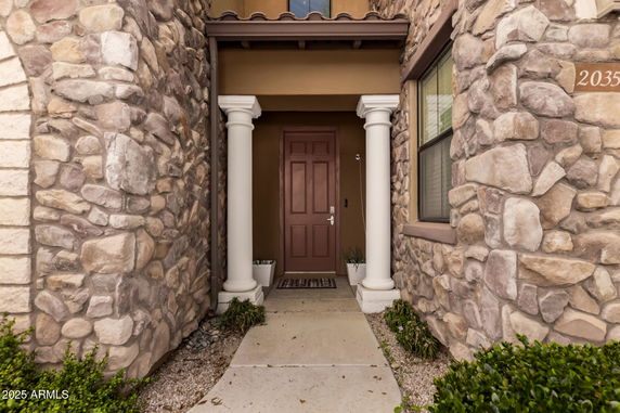 Front entrance of a house with stone facade and two white columns.